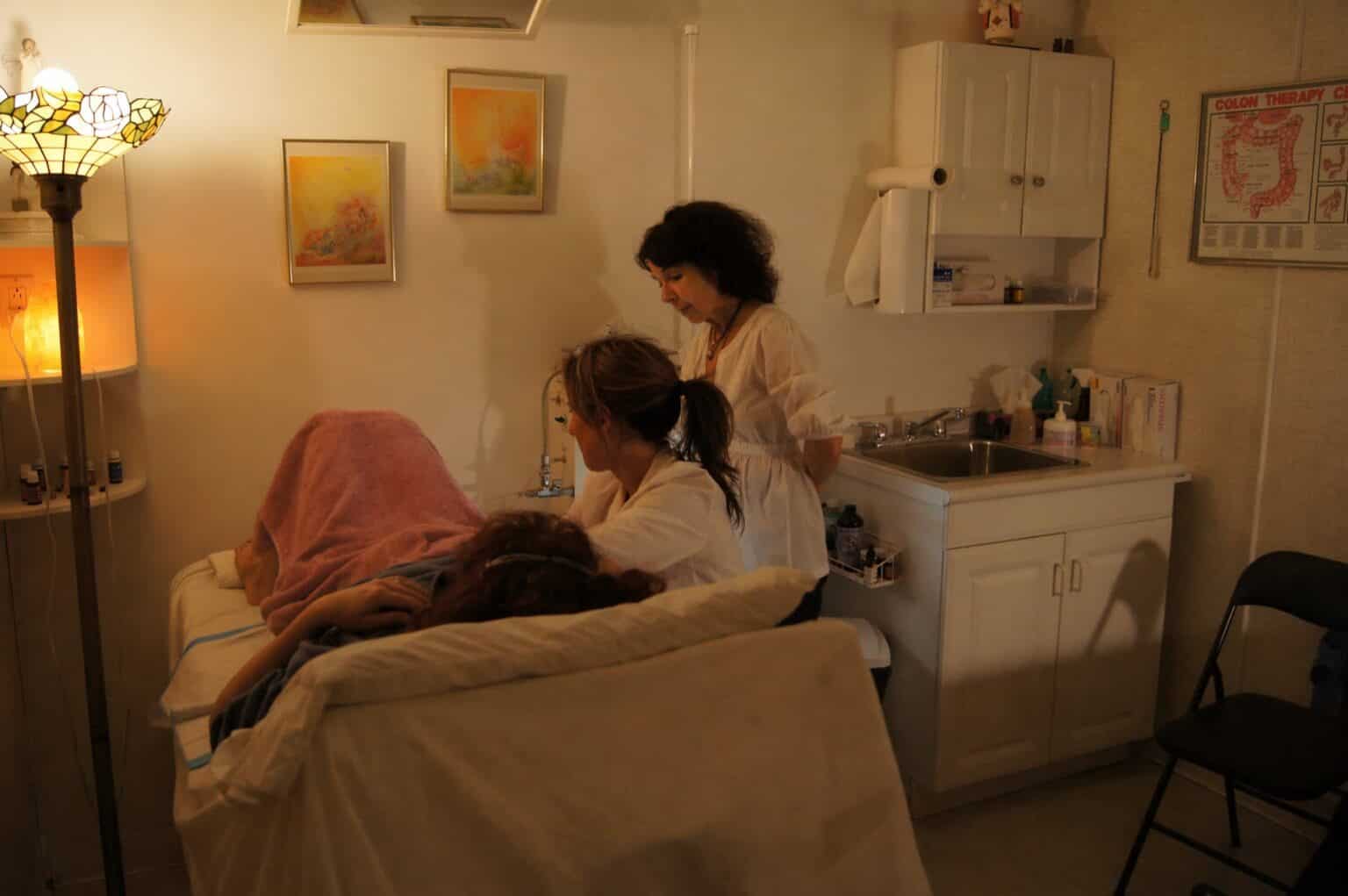 Treatment in a serene room with a client receiving care from two professionals.