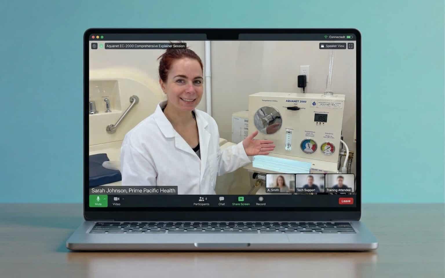 Woman in a lab coat demonstrating the Aquanet EC-2000 machine during a virtual training session on a laptop.