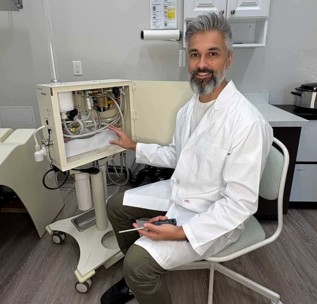 Friendly Technician servicing colon hydrotherapy system in clinical setting.