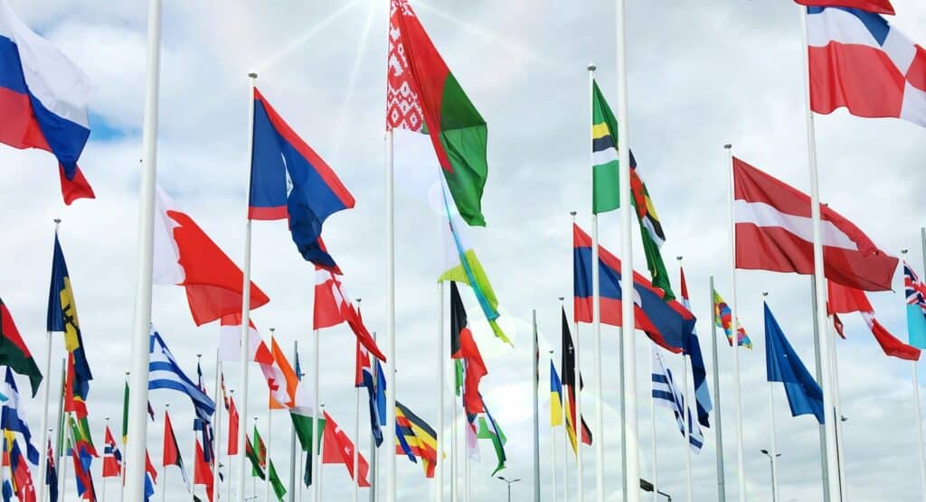 Dozens of international flags waving under a cloudy sky, symbolizing global unity and diversity.