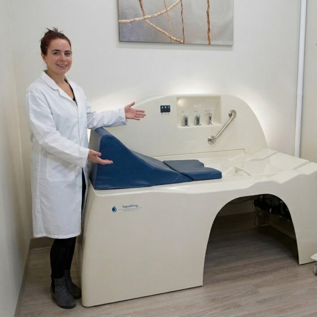 A professional in a lab coat presents a modern AquaWing hydrotherapy table in a clean treatment room.